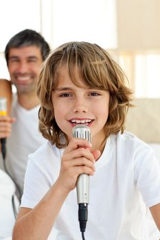 Little boy singing with a microphone sitting on bed