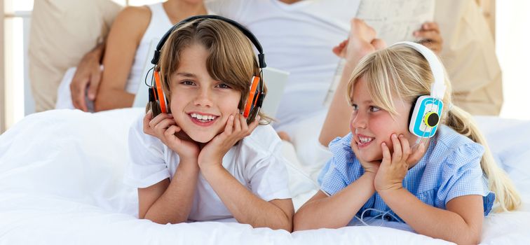 Close-up of brother and sister listening music lying on bed