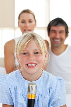 Cute little girl singing with a microphone sitting on her parent's bed 