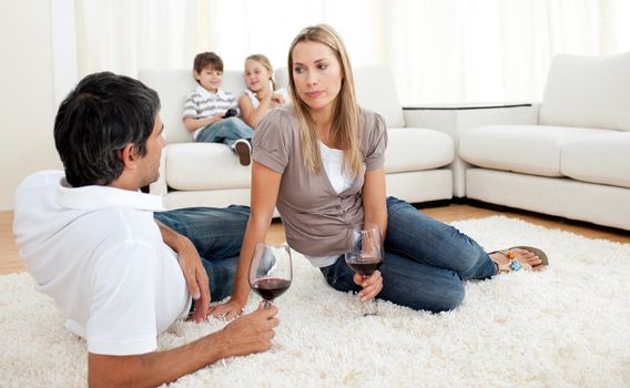 Romantic couple talking with glasses of wine lying on the floor