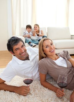 Smiling lovers drinking wine lying on the floor in the living room