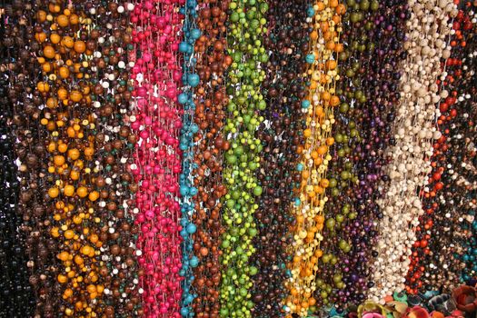 Strings of colorful carved and dyed tagua nut beads hanging for sale at the outdoor craft market in Otavalo, Ecuador