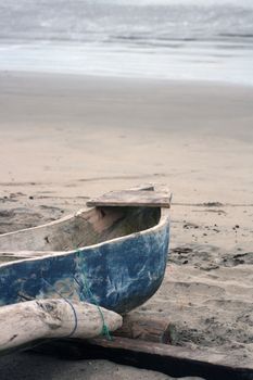 A small blue fishing boat pulled onto the sandy beach of the Pacific Ocean in Tonsupa, Ecuador