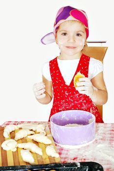 Little girl make and eat croissant studio shot