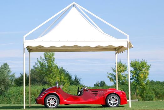Fast red cabriolet car under white tent