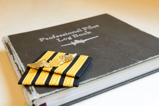 Four bar sign and golden metal wing of pilot put on the old pilot log book.