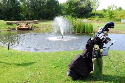 Golf bag with clubs and water behind