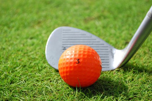 Golf club and orange golf ball