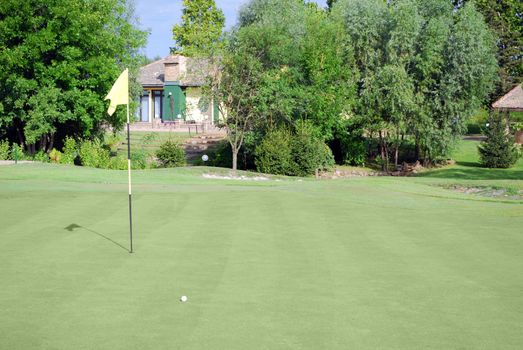Golf course with yellow flag and ball