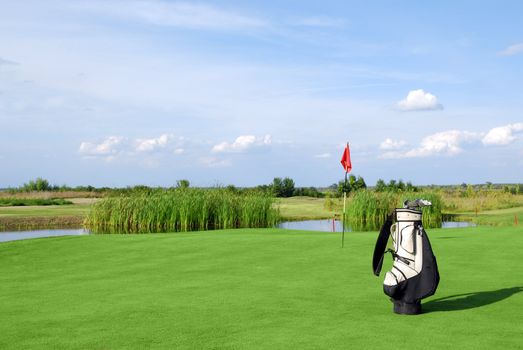 Golf field with flag and golf bag