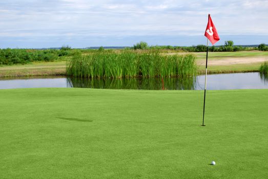Golf field with red flag and ball