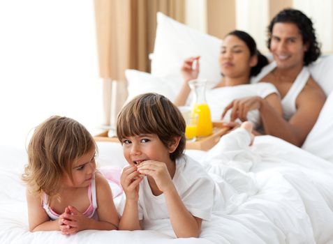 Children having breakfast with their parents in the bedroom