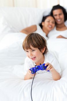 Cute little boy playing video games lying on the bed 