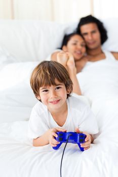 Liitle boy playing video games with parents in the background