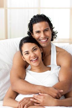 Attractive man hugging his wife lying on the bed. Concept of love.