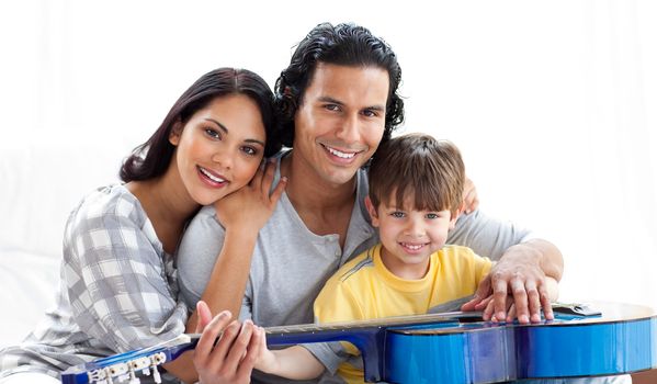 Caring parents playing guitar with their son at home