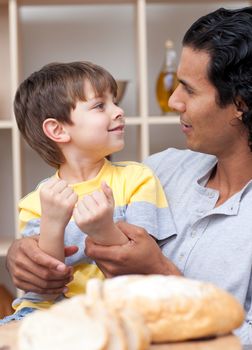 Cute little boy and his father cutting bread in the kitchen