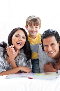 Jolly family reading book together lying on the floor