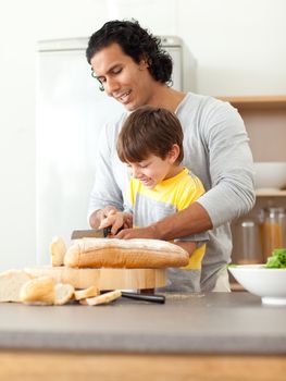 Attentive father helping his son cut some bread in the kitchen