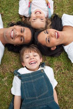 Adorable little boy lying in a circle with his family in a park