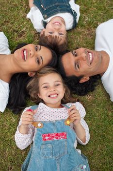 Cute little girl lying in a circle with her family in a park