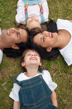 Cute children and their parents lying on the grass in a park