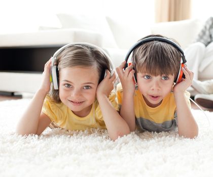 Close-up of children listening music with headphones lying on the floor