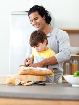 Charming father cutting bread with his son in the kitchen