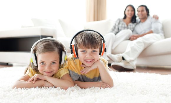 Adorable siblings listening music with headphones lying on the floor