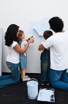 Loving parents helping their children paint a wall