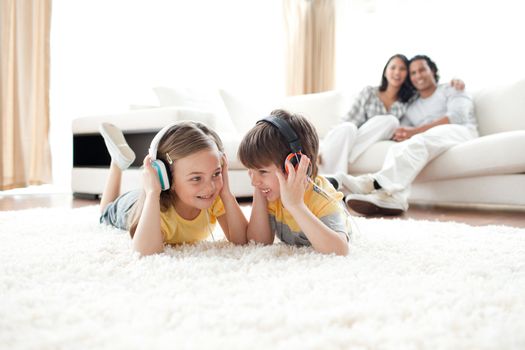 Brother and sister listening music with headphones lying on the floor