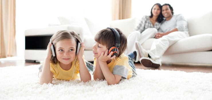 Little boy and little girl playing on the floor with headphones in the living room