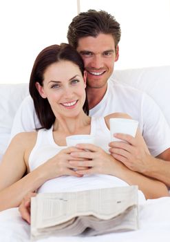 Romantic couple drinking coffee and reading newspaper