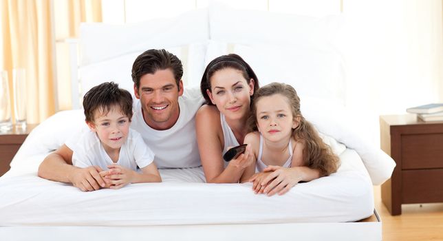 Cute siblings and their parents lying on the bed