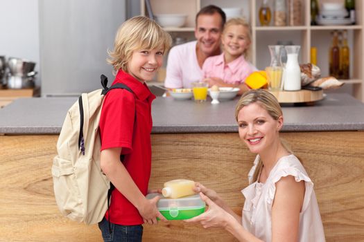 Attentive mother packing the school lunch to his son in the kitchen