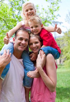 Smiling parents giving their children piggy-back ride in a park