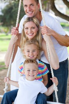 Jolly family swinging in a park