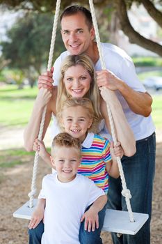 Happy family swinging in a park