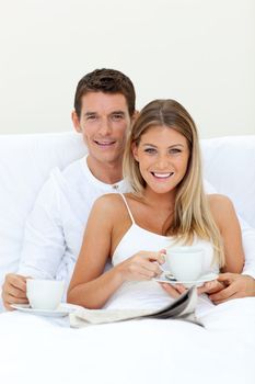 Romantic couple drinking coffee lying on their bed. Concept of love.