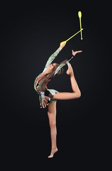 Young cute woman in gymnast suit show athletic skill on black background