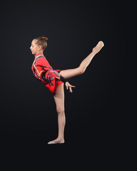 Young cute woman in gymnast suit show athletic skill on black background