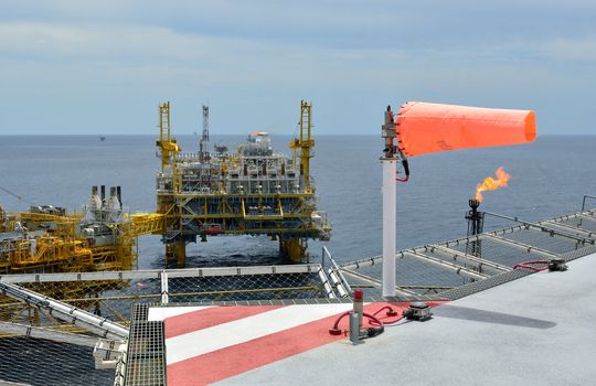 The wind sock is set on the oil rig to showing wind direction for  helicopter landing .