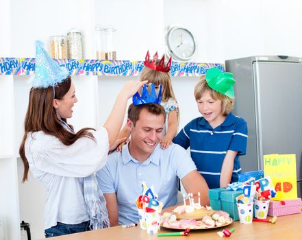Delighted man celebrating his birthday with his wife and his children in the kitchen