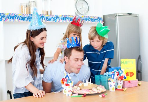 Elegant man celebrating his birthday with his wife and his children in the kitchen