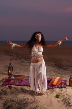 Female oriental dancer on a beach at dusk