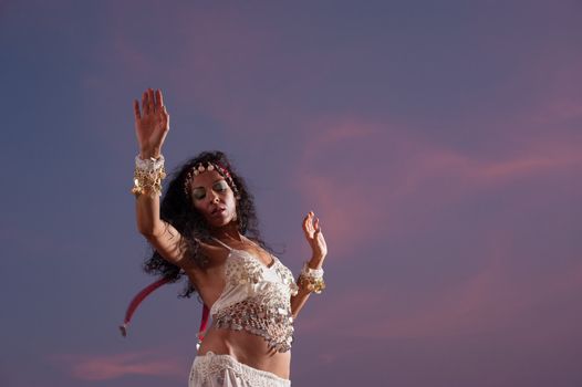 Expressive oriental dancer against an evening sky