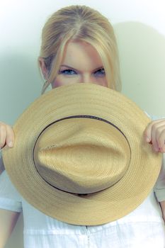 A beautiful girl with a straw hat against a white wall
