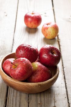 A bowl of red apples on the wooden table