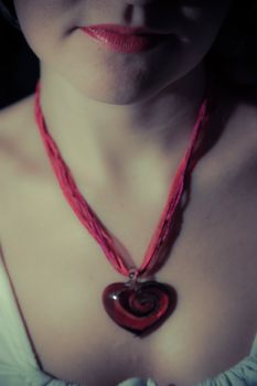 A girls lips with a red heart pendant