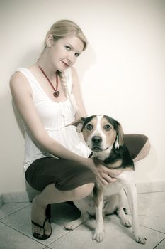 A girl with her dog against a white wall